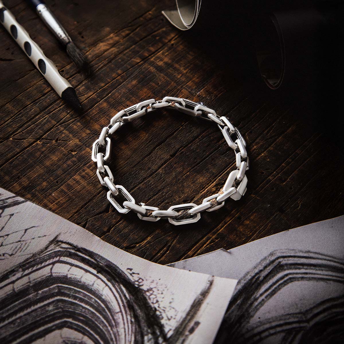 Nahaufnahme des Aqdas-Sterlingsilber-Gliederarmbandes mit Skizzenpapier. Ninetwofive