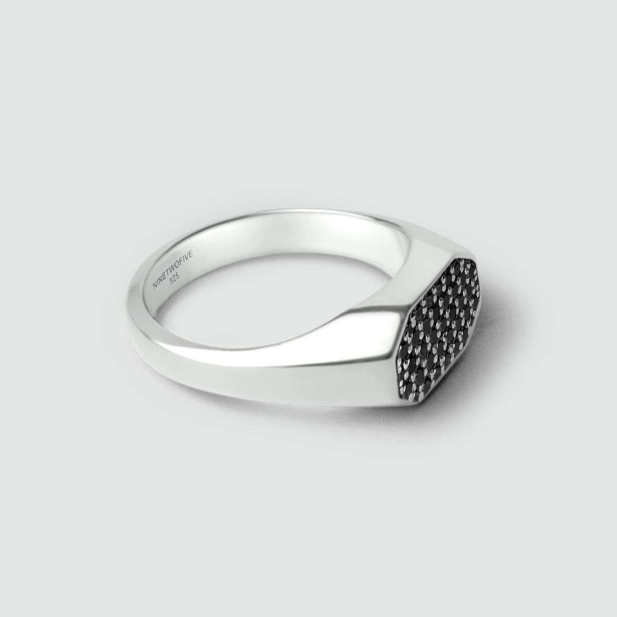 Mens Silver signet ring with black diamonds on a light gray background