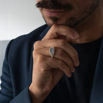 Man wearing a silver signet ring with a black diamonds, close-up of hand