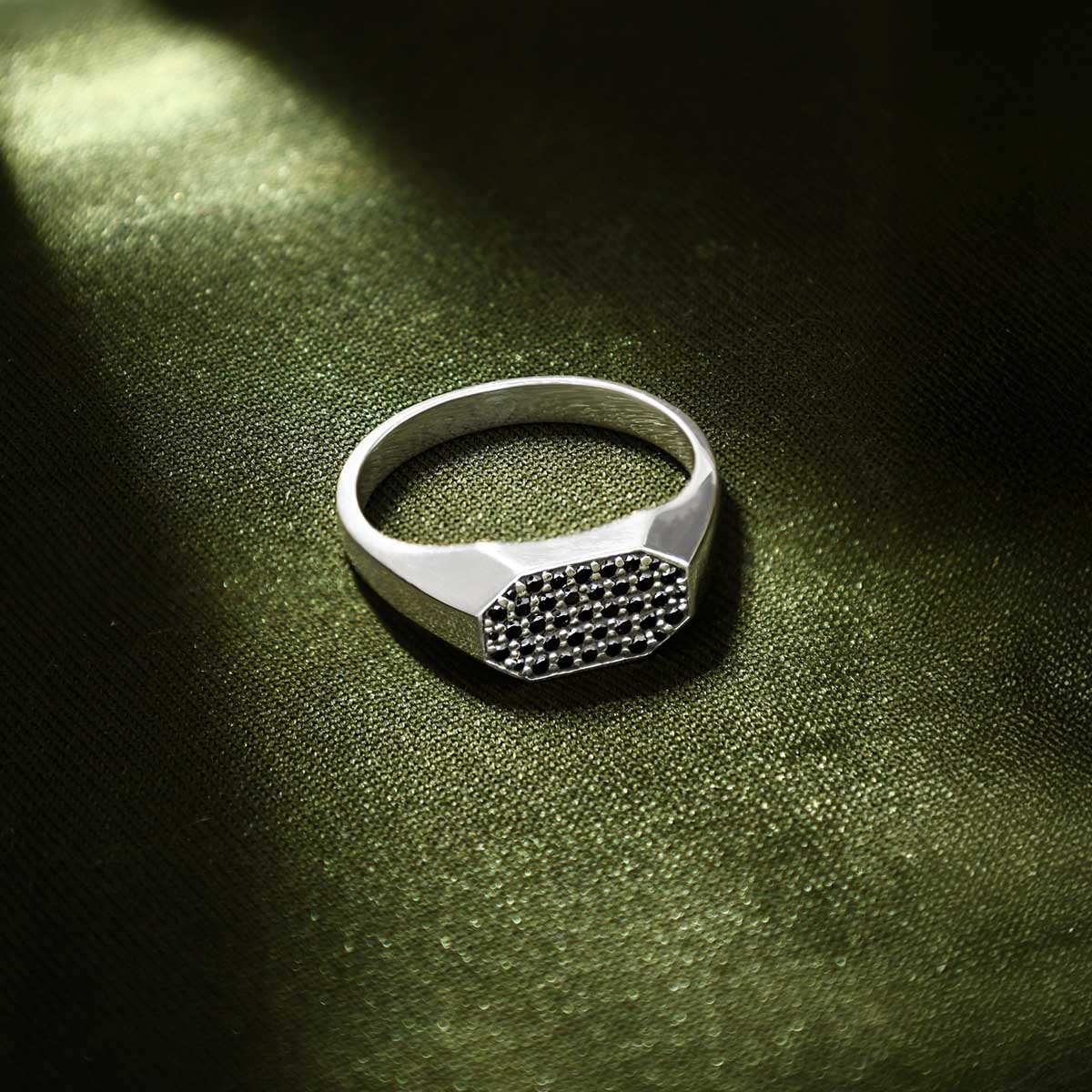 Azhar black diamond sterling silver men’s signet ring displayed on a green cloth from Ninetwofive.