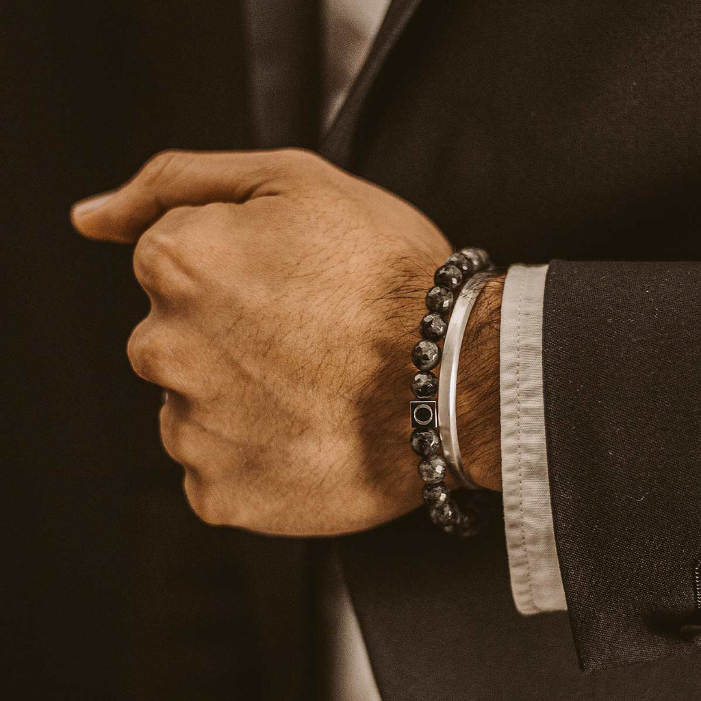 A man in a suit is wearing a black bracelet.