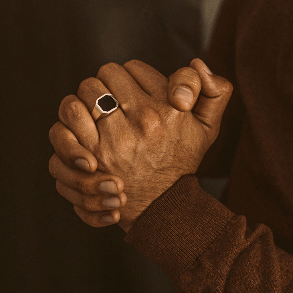 Een man die zijn handen in elkaar klemt terwijl hij een ring draagt.