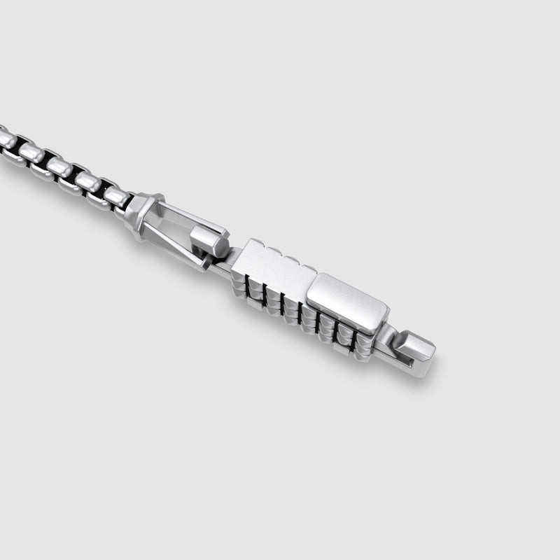 Nahaufnahme eines silbernen Venezianerketten-Armbandverschlusses vor hellgrauem Hintergrund