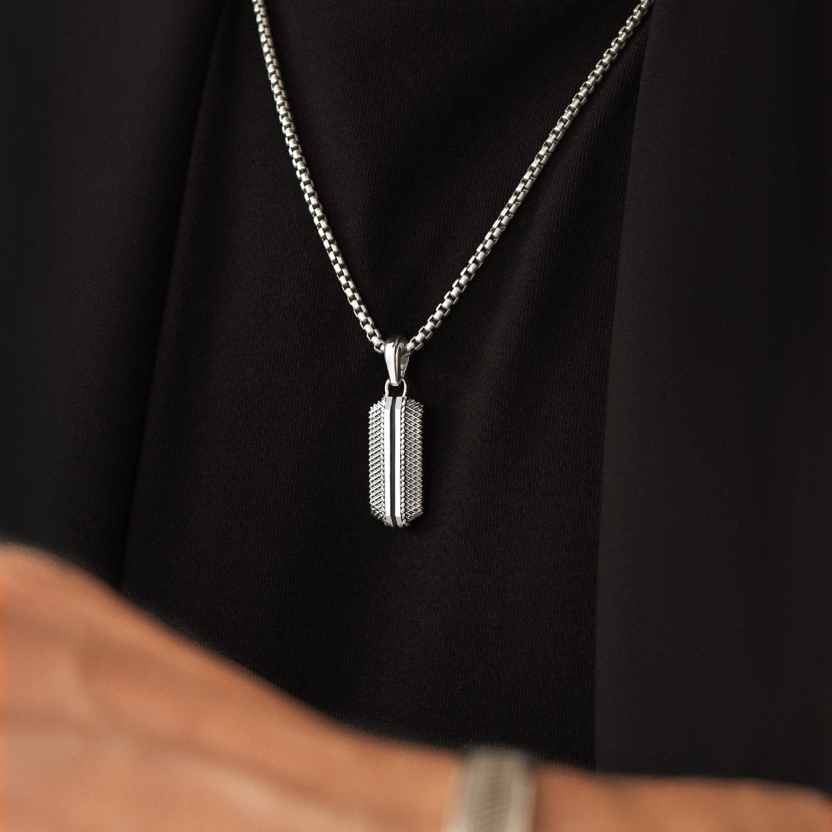 Close-up van mannelijk model met Kaliq geoxideerde sterling zilveren hanger van Ninetwofive.