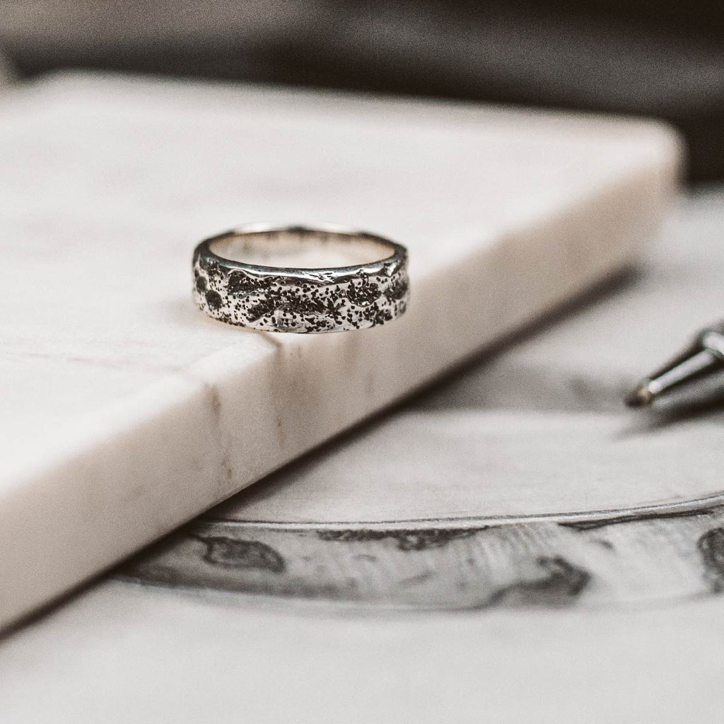 Ein silberner Ring liegt auf einem Tisch.