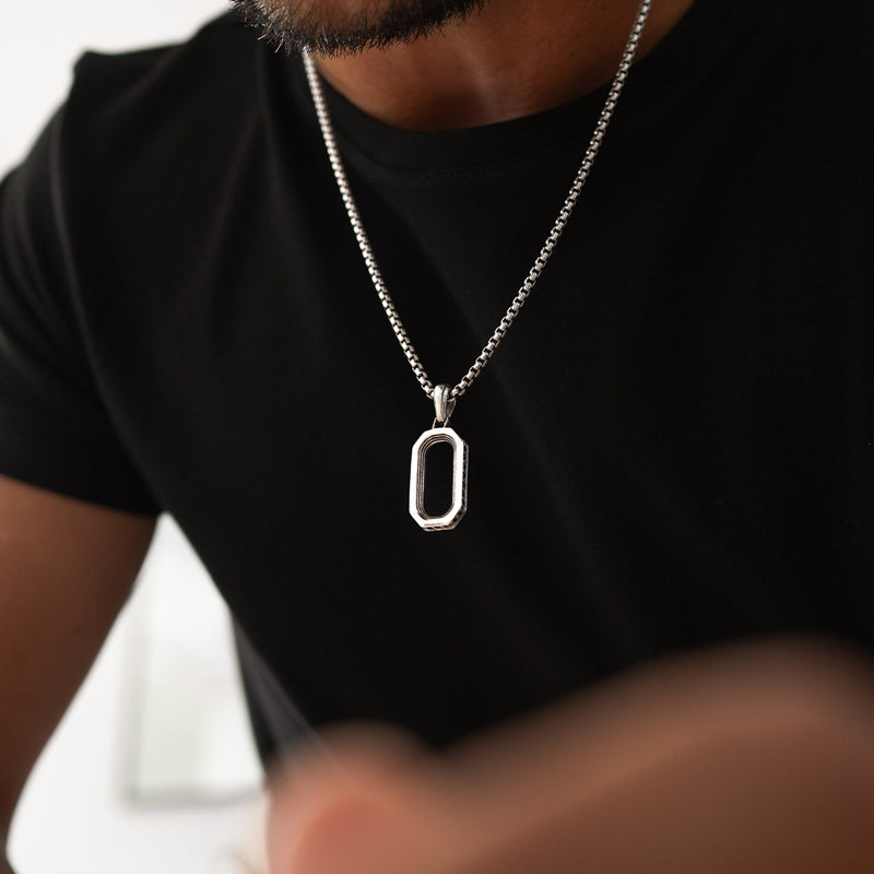 Un homme portant le pendentif en argent en forme d'arche de Durwās, assorti à une chemise foncée – Ninetwofive