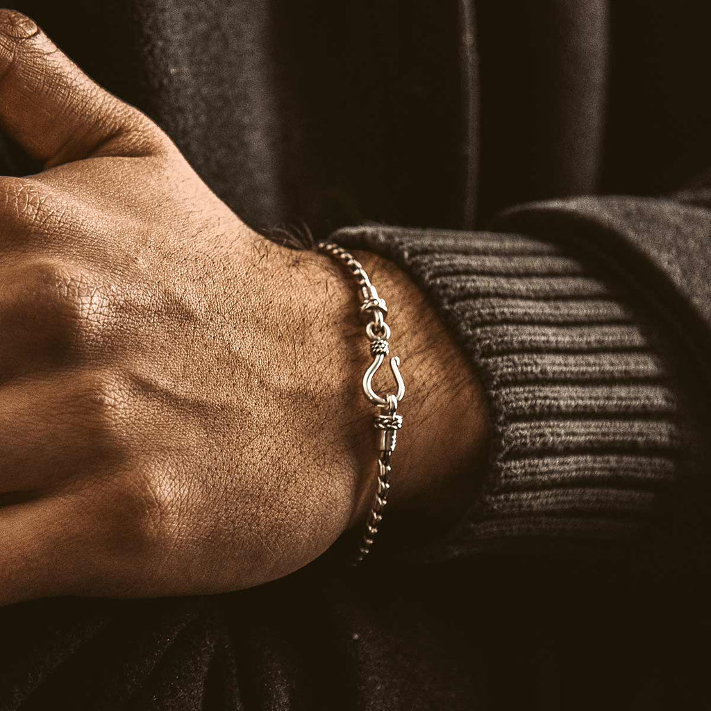 A man's wrist with a silver bracelet.