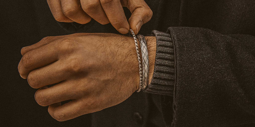 A man is putting a bracelet on his wrist.