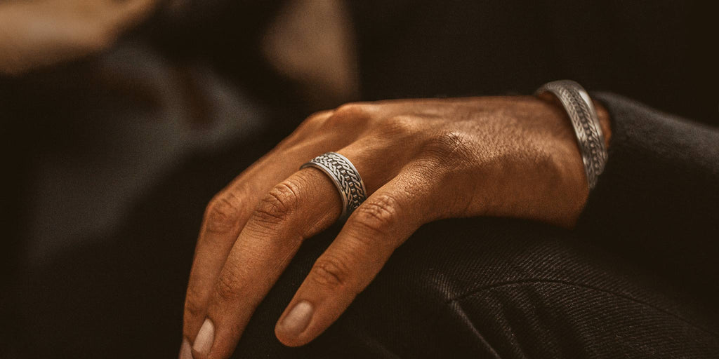 Die Hand eines Mannes ist mit einem silbernen Ring geschmückt.