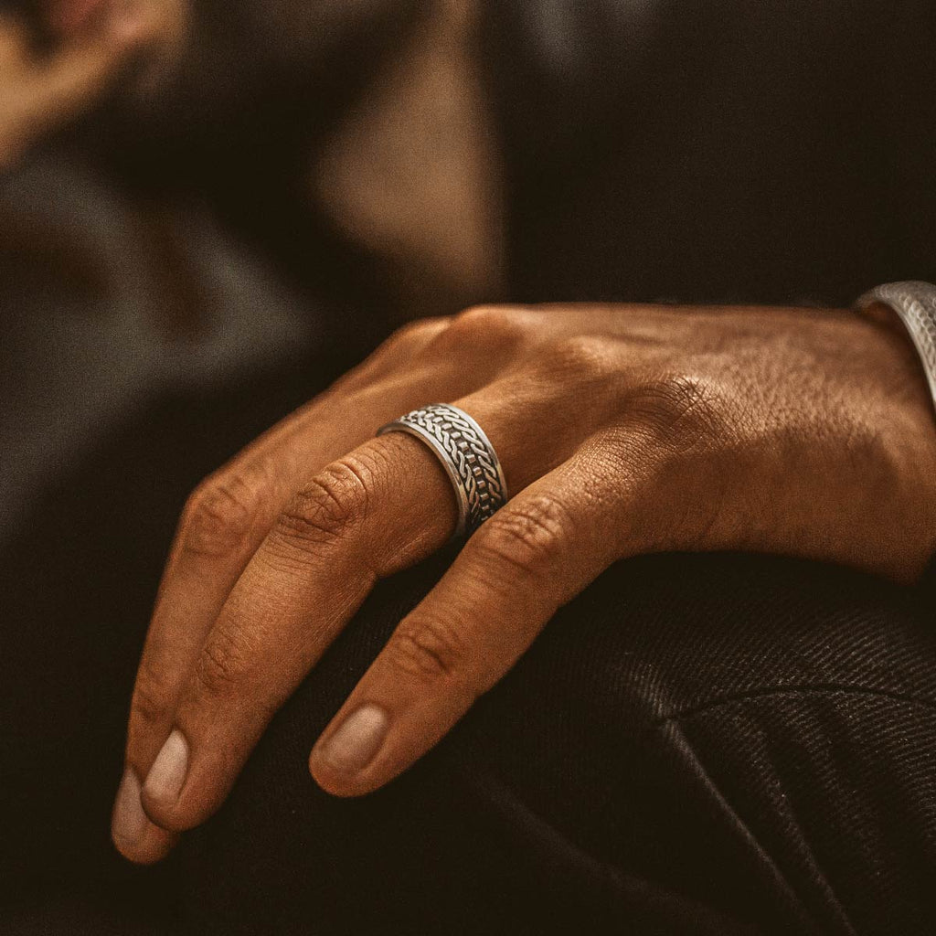 A man wearing a mens silver ring.
