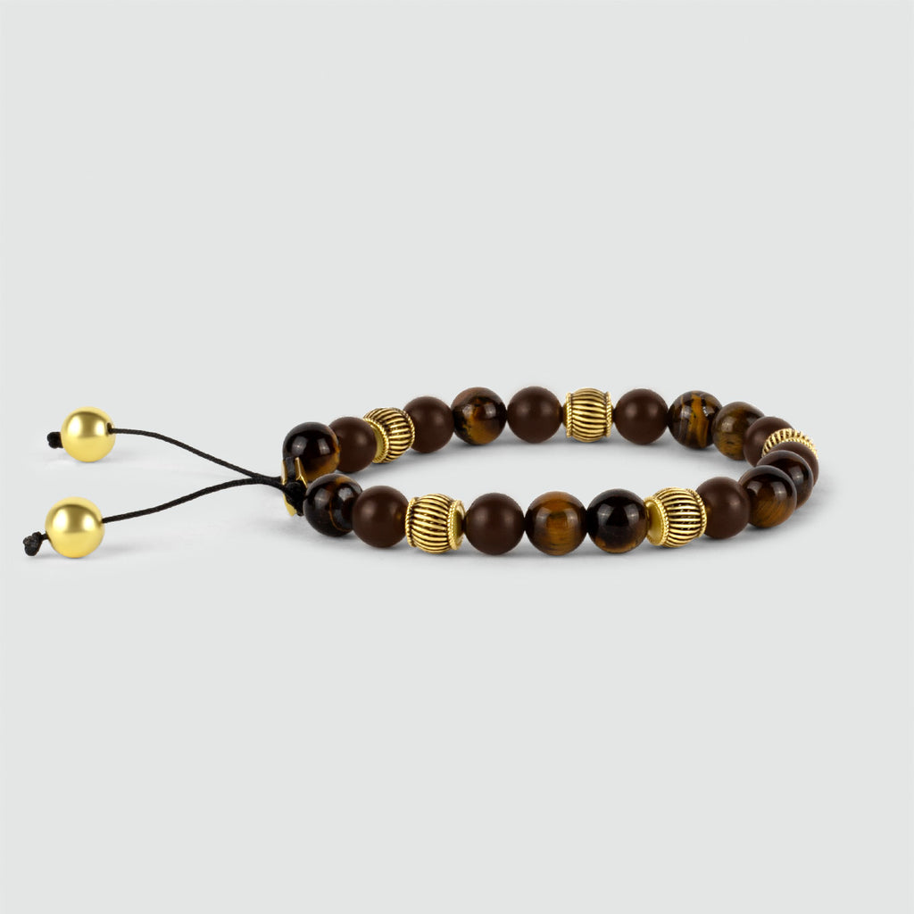 The Kaliq - Adjustable Tiger Eye Beaded Bracelet in Gold 8mm is brown with accents of gold, featuring the mesmerizing tiger eye gemstone.