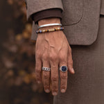 Man in a brown suit wearing the Halloween Treat natural stone bracelet with silver rings