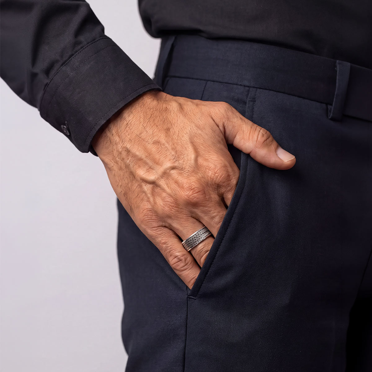 Hani silver spinner ring worn with dark trousers, hand in pocket