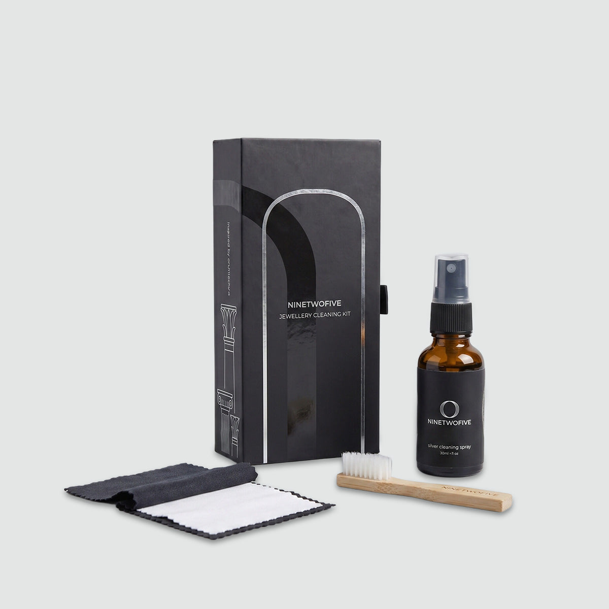 Sieradenreinigingsset met spuitfles, borsteltje en verpakking op een lichtgrijze achtergrond