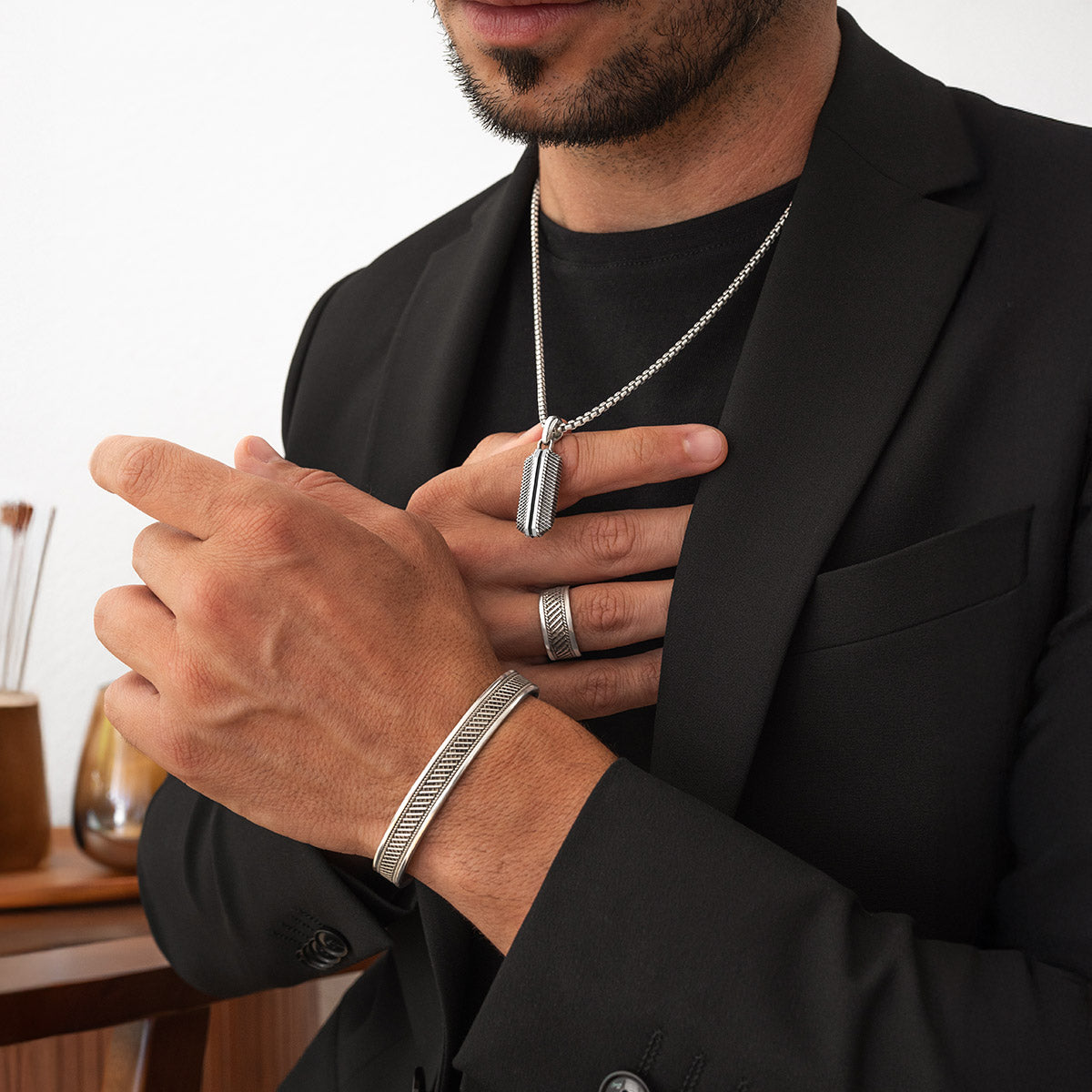 Model draagt Kaliq 925 zilveren armband, ring en hanger, gestyled met een zwarte blazer. Ninetwofive.