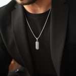 Close-up of Kaliq oxidised sterling silver pendant with chain, worn with a black blazer. Ninetwofive