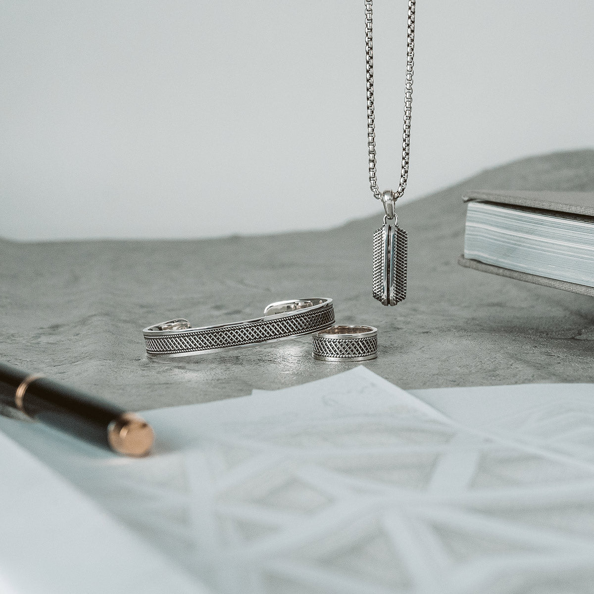 Toont Kaliq sterling zilveren herenhanger, ring en bangle voor een set van Ninetwofive. 