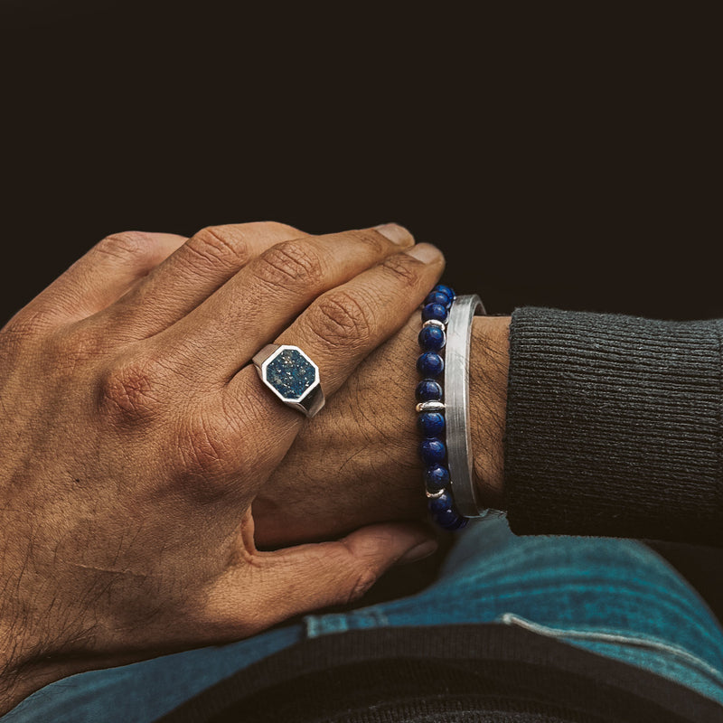 Man in black sweater and blue denim wears Kadar blue beaded bracelet, mens signet ring and silver cuff by Ninetwofive.
