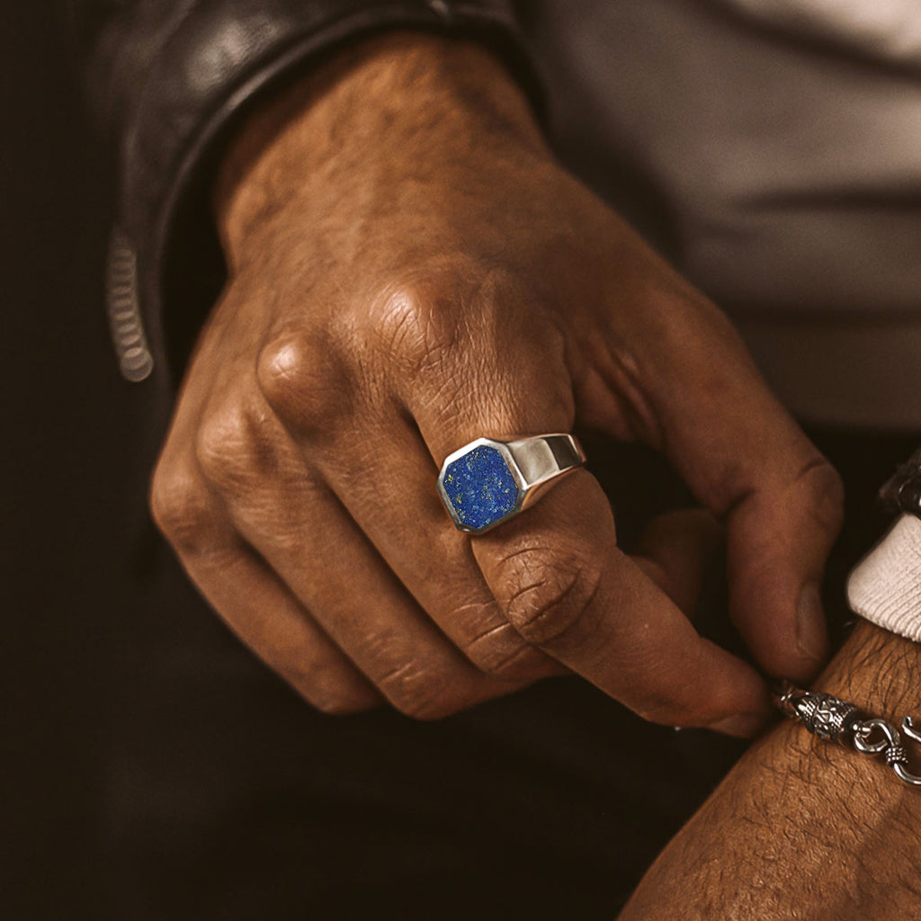 Ein Mann trägt einen Ring mit einem blauen Stein.