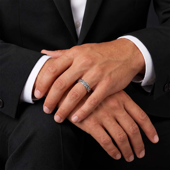 Man in a black suit with hands crossed, wearing the Latif braided silver ring