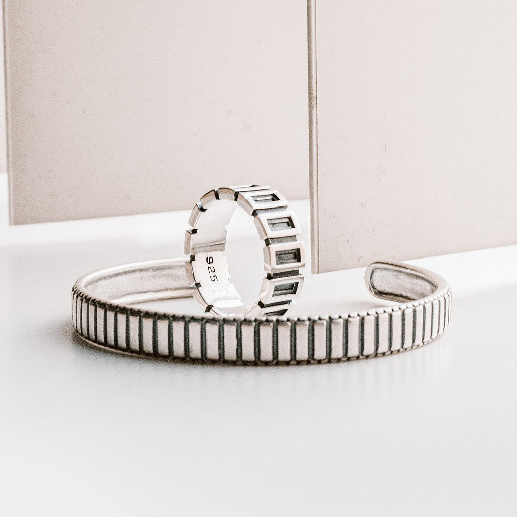 Een zilveren ring en armband op een tafel.