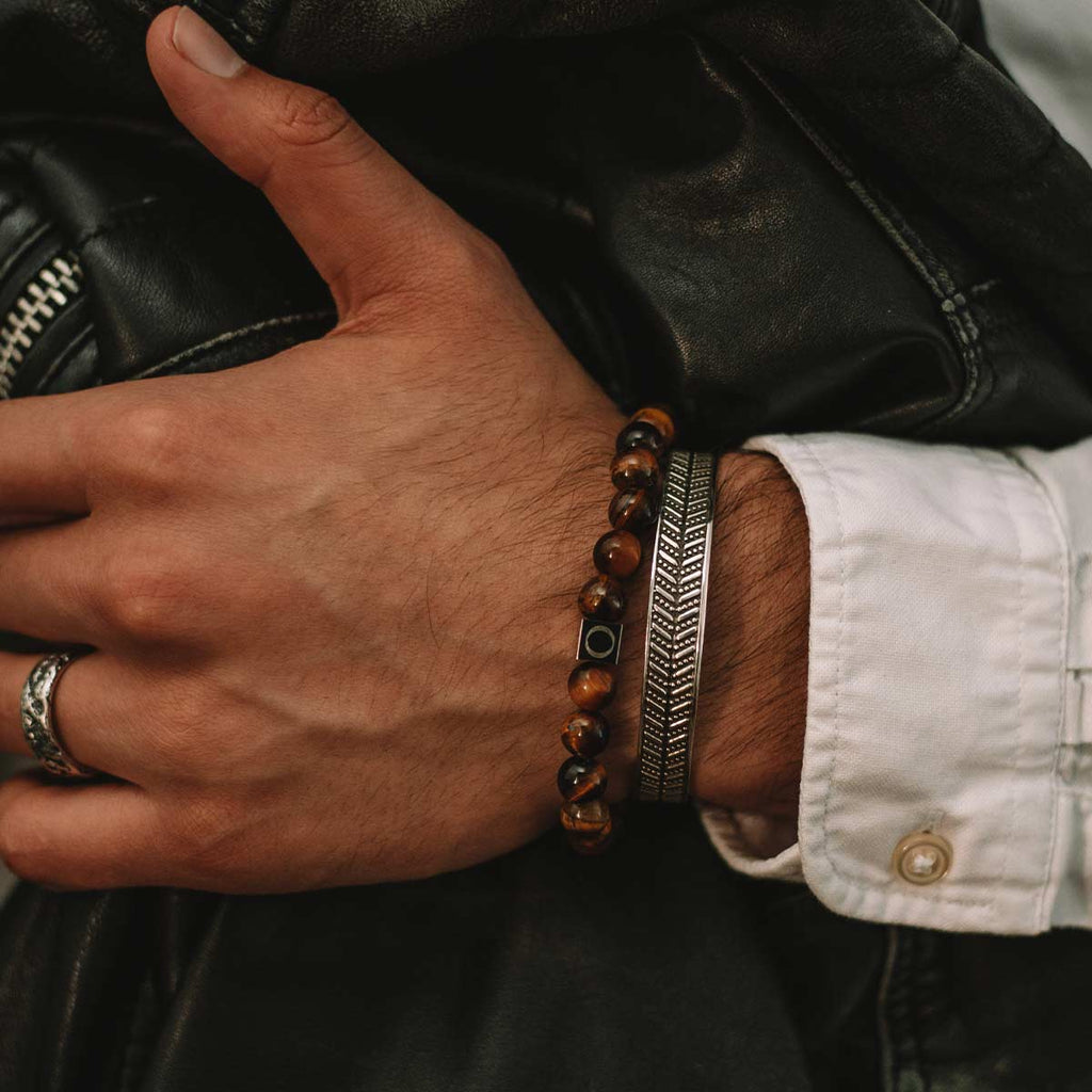 A man wearing a bracelet with tiger eye beads.