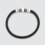 A black braided leather bracelet with a silver-toned metal clasp featuring a central square plate and textured side details, shown on a light gray background.