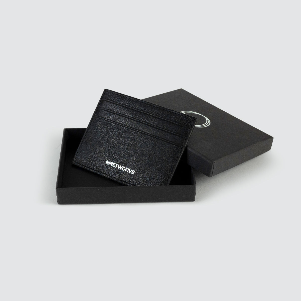 Zwart lederen herenportemonnee in een geopende box van Ninetwofive, met het Ninetwofive in reliëf.