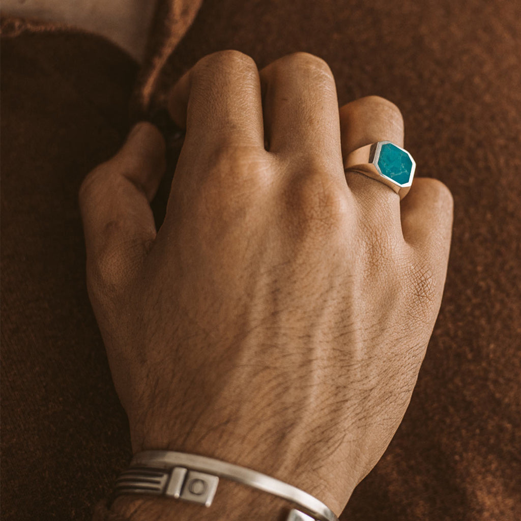 A man wearing a ring with a turquoise stone.