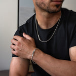 Homme portant une chemise noire avec un boîte en argent et une boîte collier.