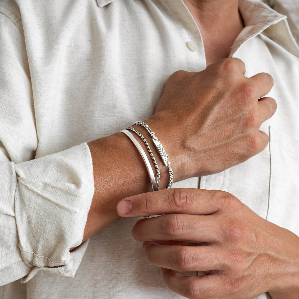 Man draagt sterling zilveren byzantijnse armband Ramsi van Ninetwofive met andere zilveren armbanden.