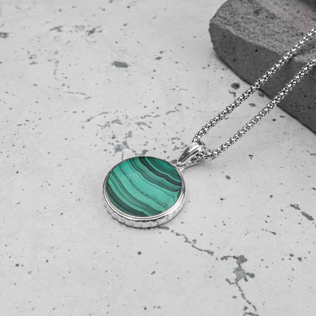 A necklace with a green stone on it can be paired with a personalized mens bracelet.