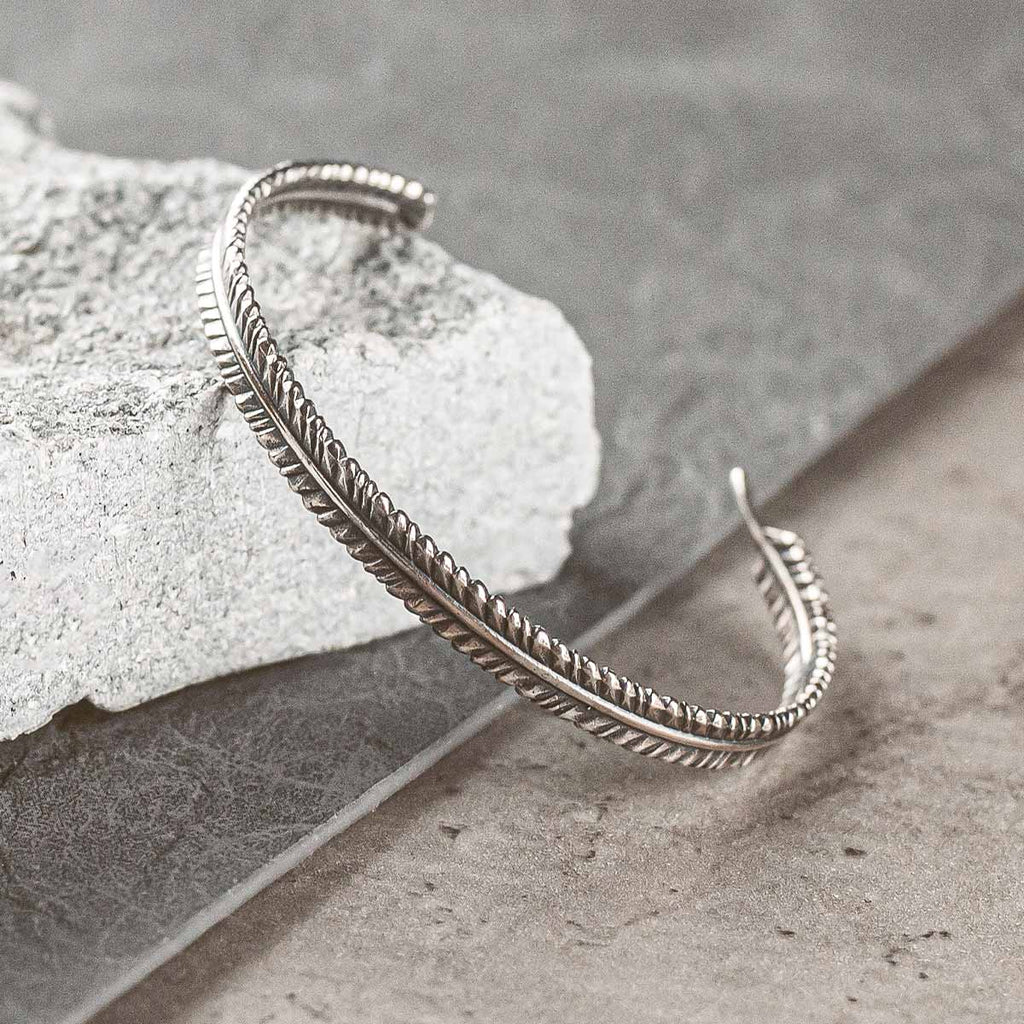 A silver bracelet on top of a rock.