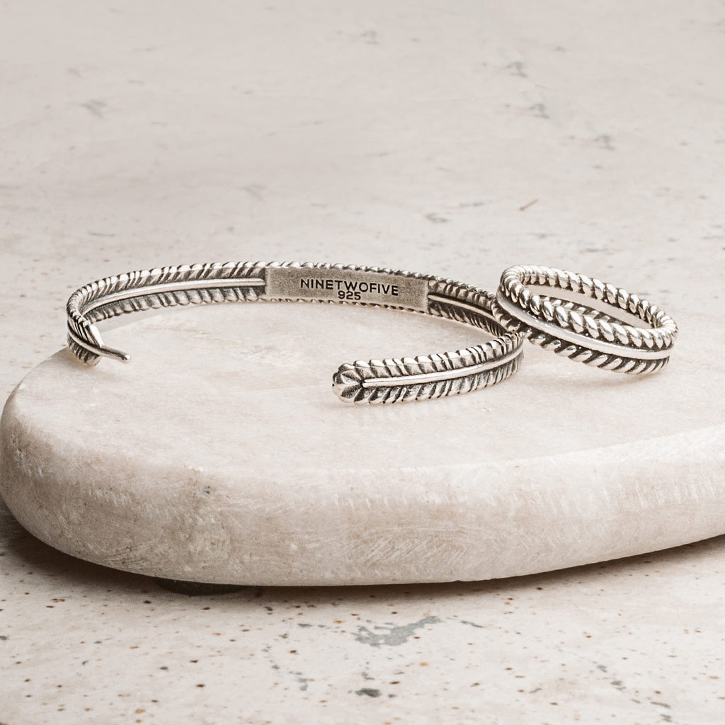 A silver cuff bracelet on a stone.