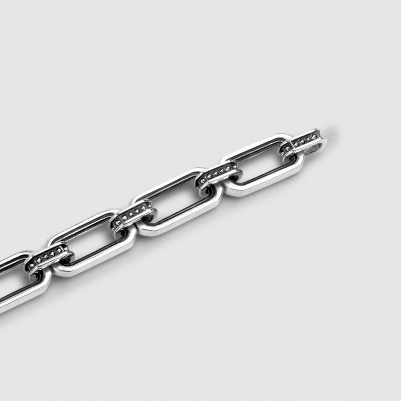 Macrofoto van de Aqwas-zilveren armband, waarop de gepolijste rechthoekige schakels en de gestructureerde details met noppen goed tot hun recht komen.