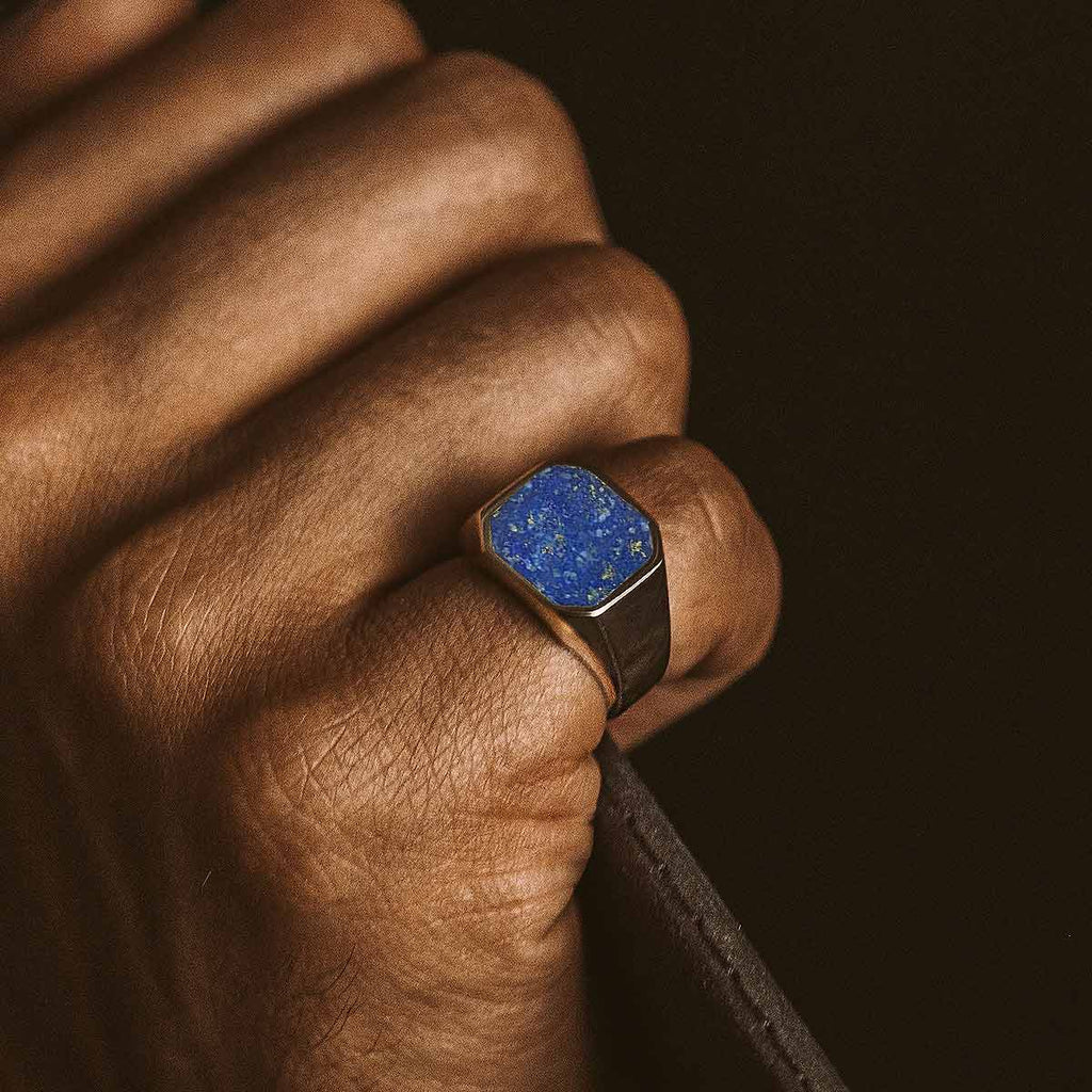 A man wearing a ring with a blue stone.
