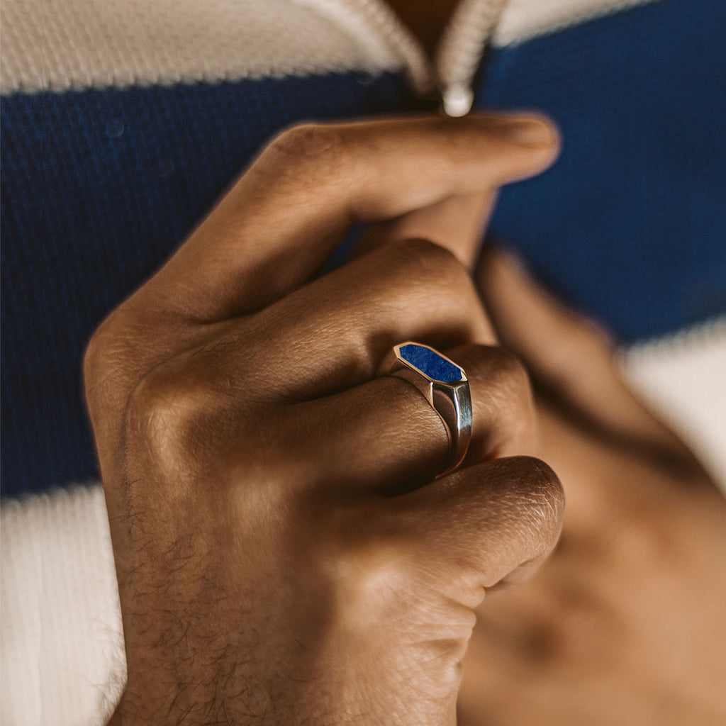 A man wearing the Rafiq - Elegant Lapis Lazuli Signet Ring 7mm with an engraved blue stone.