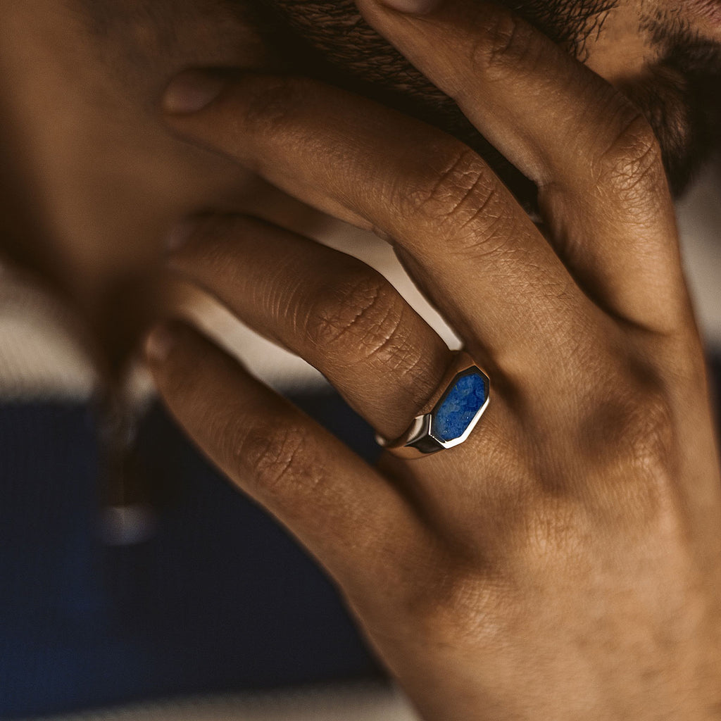 A man adorned with a Rafiq - Elegant Lapis Lazuli Signet Ring 7mm featuring a blue stone.