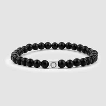 A Aswad - Matt Black Beaded Bracelet 6mm with a silver charm, featuring an exquisite onyx stone.