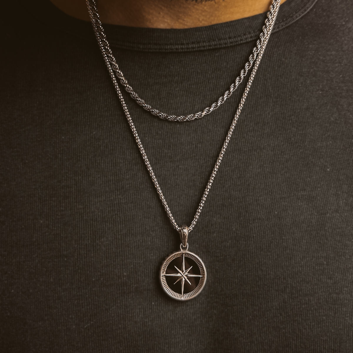 Een man draagt een Safar - Sterling Zilveren Onyx Kompas Hanger ketting.