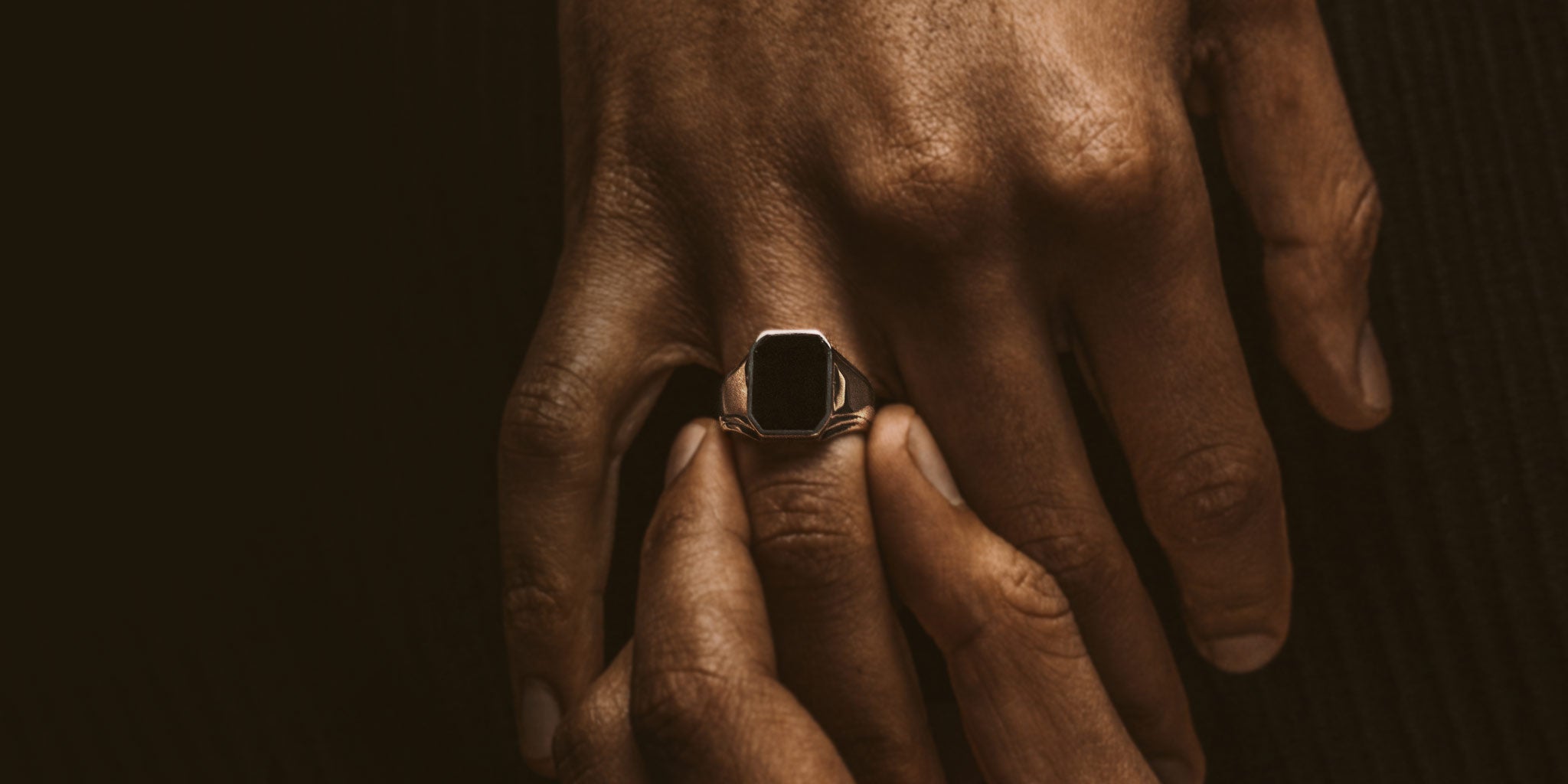 A hand holding a black stone ring.