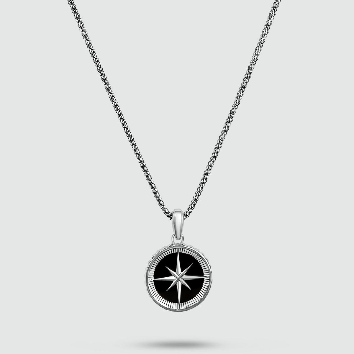 Een zwart-witte Safar - Sterling Zilveren Onyx Kompas hanger aan een zilveren herenketting.
