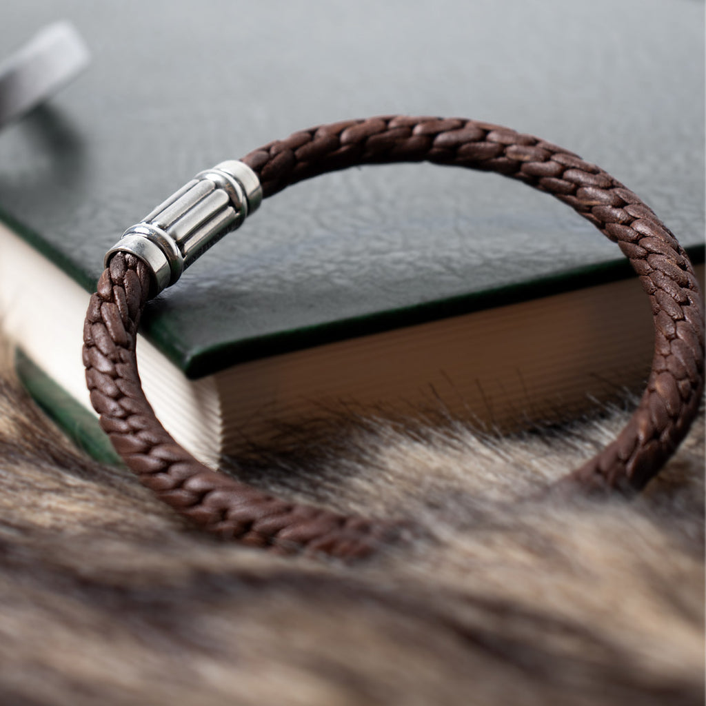 Un bracelet en cuir marron posé sur un livre.