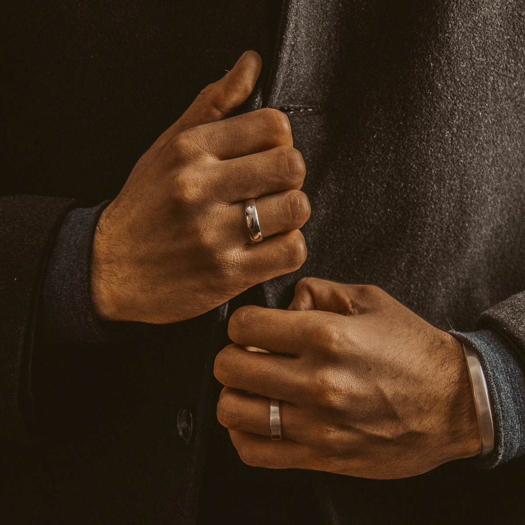 A man in a suit is putting on a wedding ring.