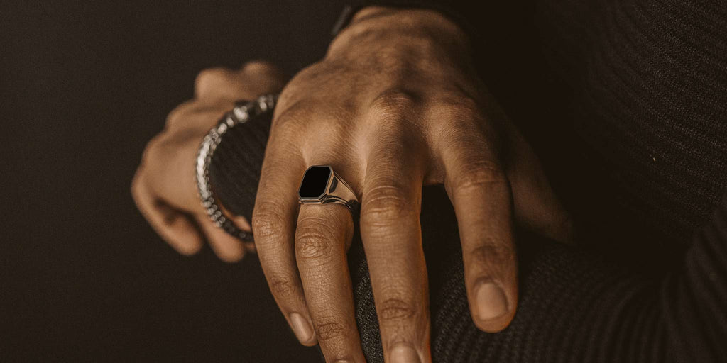 A man's hand wearing a black ring.