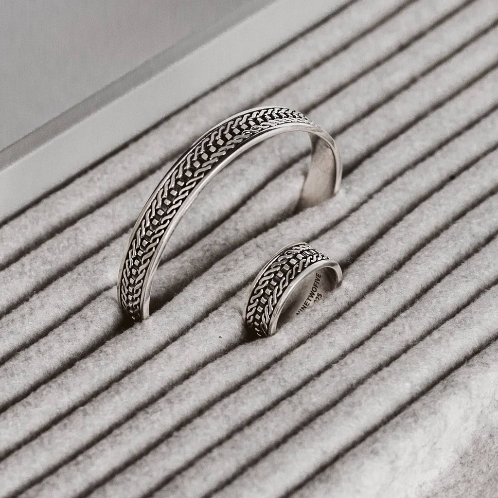 A pair of silver rings sitting on a striped surface. (Keywords: mens silver ring)