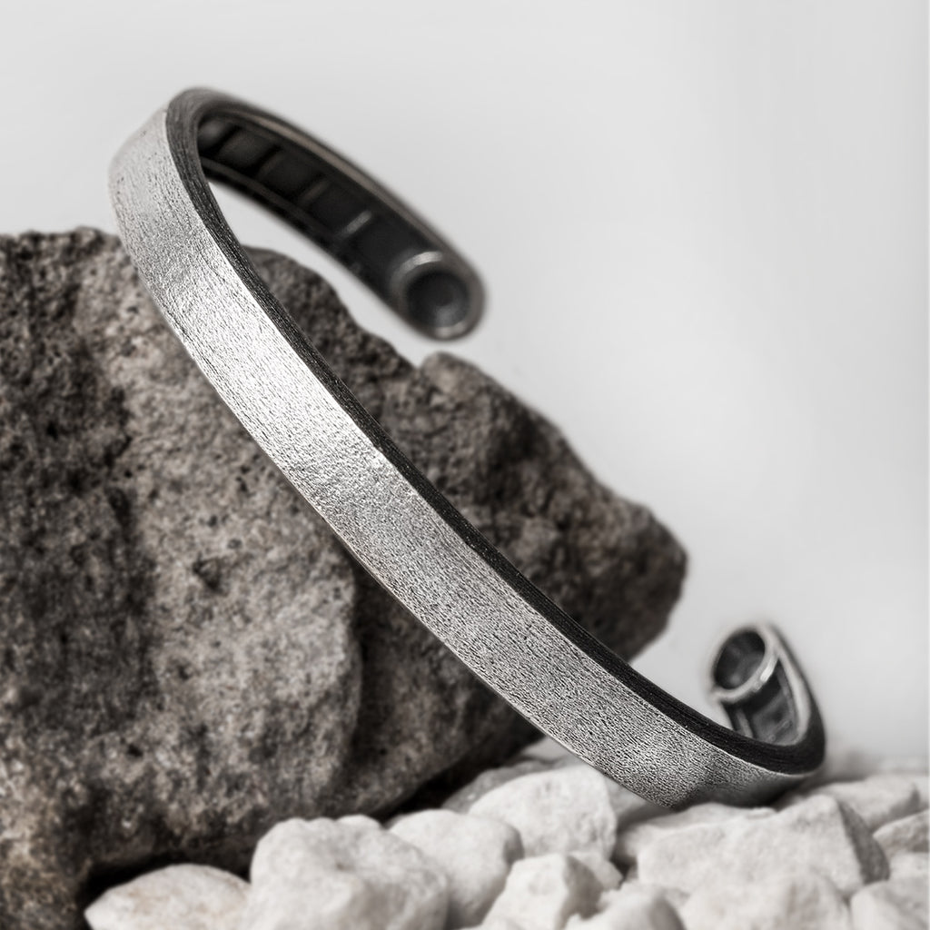 A silver cuff bracelet on a rock.
