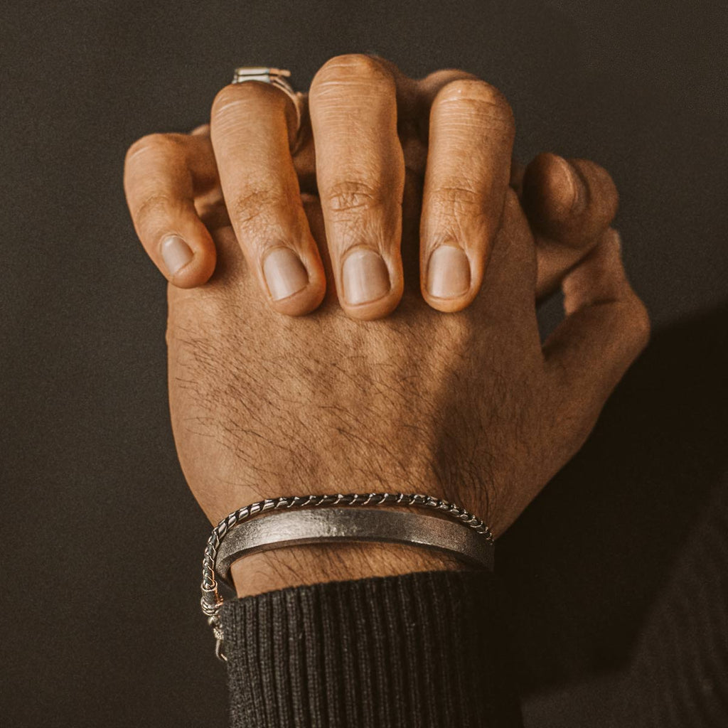 A man's hand with a bracelet on it.