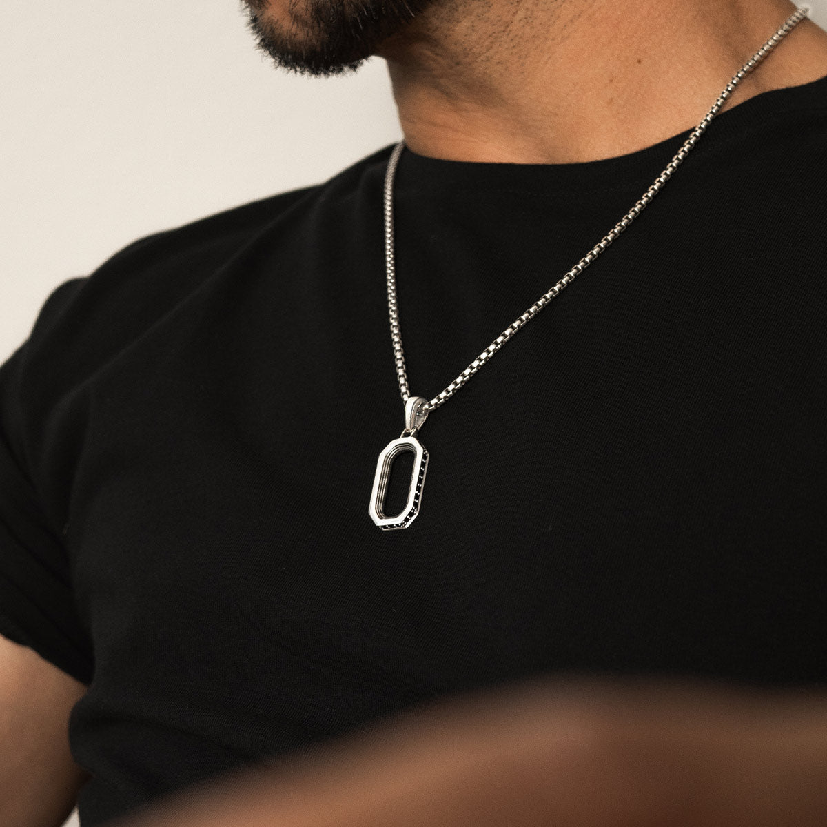 Close-up van de zilveren hanger van Durwās voor mannen, gedragen over een ronde hals - Ninetwofive