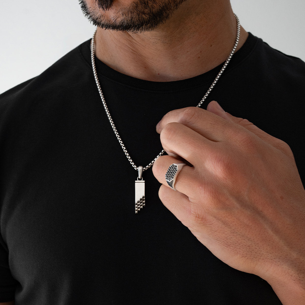 Modell-Stylings: Muqarnas-Silberanhänger und Siegelring für Herren von Ninetwofive einem schwarzen Hemd – Nahaufnahme.